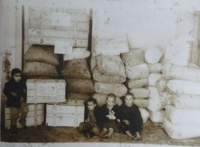 fotografie; patru copii, trei întinși pe jos, rezemați de niște saci cu alimente (8 ianuarie 1947)